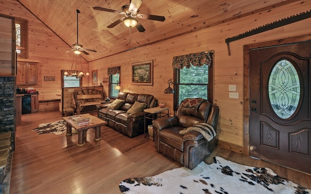 living area featuring ceiling fan, light wood finished floors, wood walls, wooden ceiling, and high vaulted ceiling