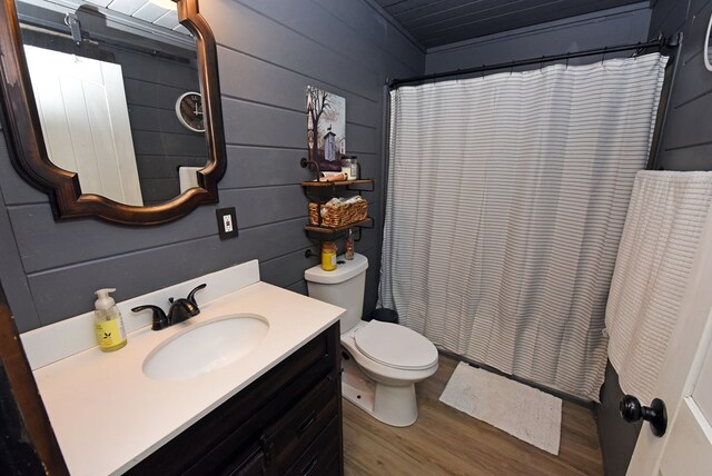 bathroom with vanity, toilet, wood-type flooring, and wooden walls