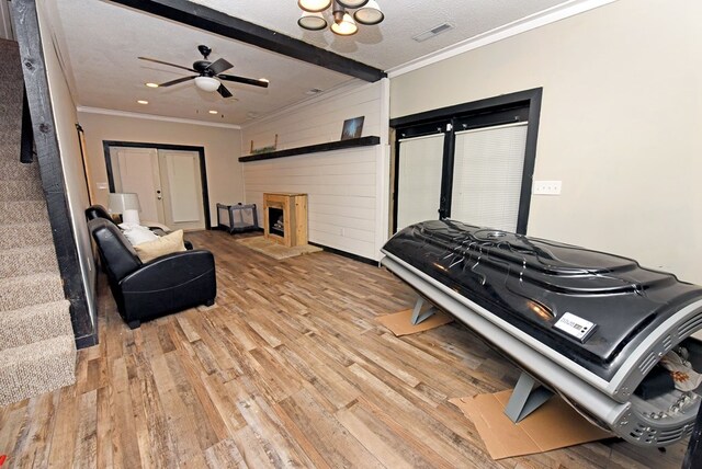 living room featuring a textured ceiling, ceiling fan, beamed ceiling, and light wood-type flooring