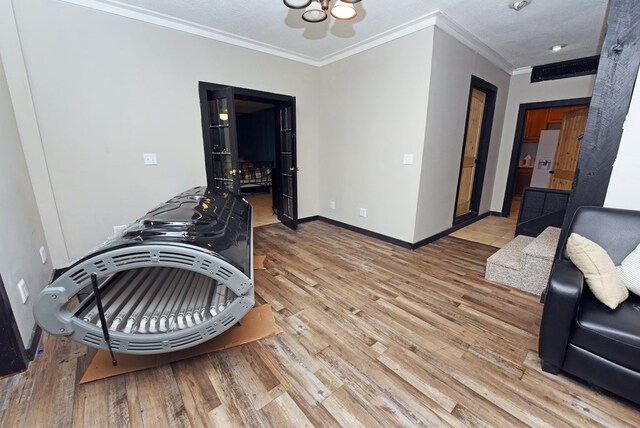 misc room with light hardwood / wood-style floors, a textured ceiling, and ornamental molding