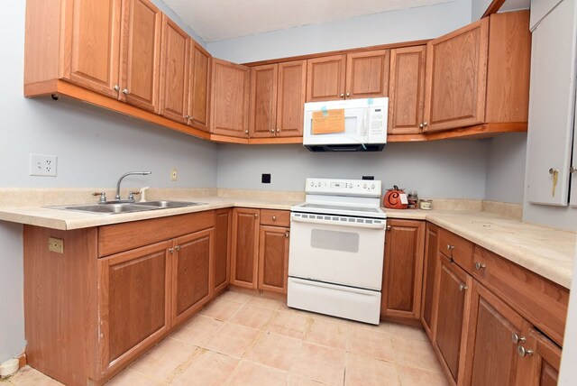 kitchen with white appliances, light tile patterned floors, a textured ceiling, and sink