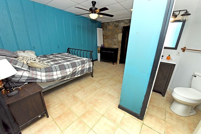 tiled bedroom with ceiling fan and a drop ceiling