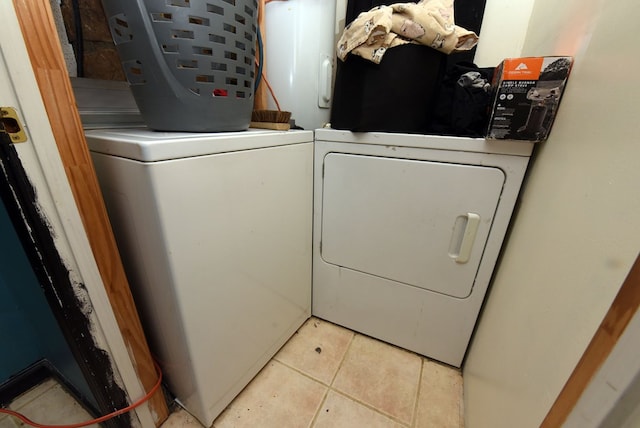 laundry room featuring water heater, light tile patterned floors, and washing machine and dryer