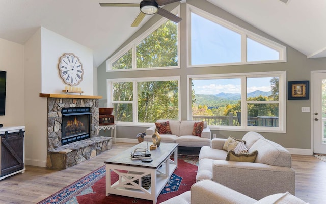 living room featuring a mountain view, vaulted ceiling, hardwood / wood-style flooring, ceiling fan, and a fireplace