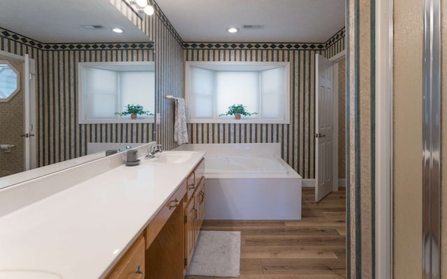 bathroom featuring hardwood / wood-style floors, vanity, a bathtub, and a textured ceiling