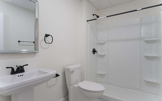 bathroom with sink, a drop ceiling, toilet, and a shower