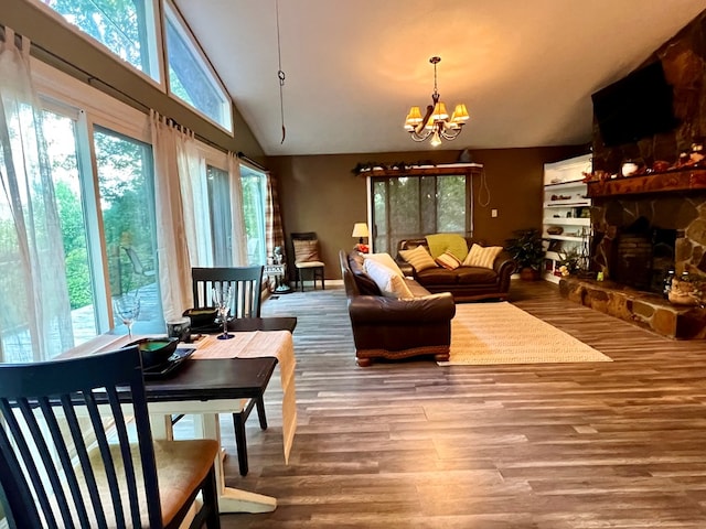 living room with lofted ceiling, plenty of natural light, an inviting chandelier, and hardwood / wood-style floors