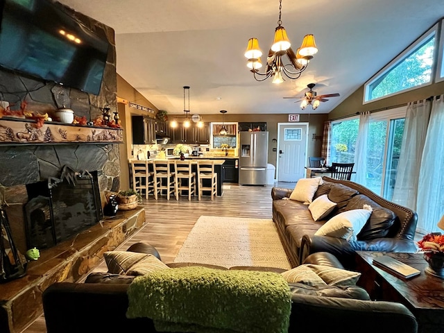 living room featuring light hardwood / wood-style floors, lofted ceiling, ceiling fan with notable chandelier, and a fireplace