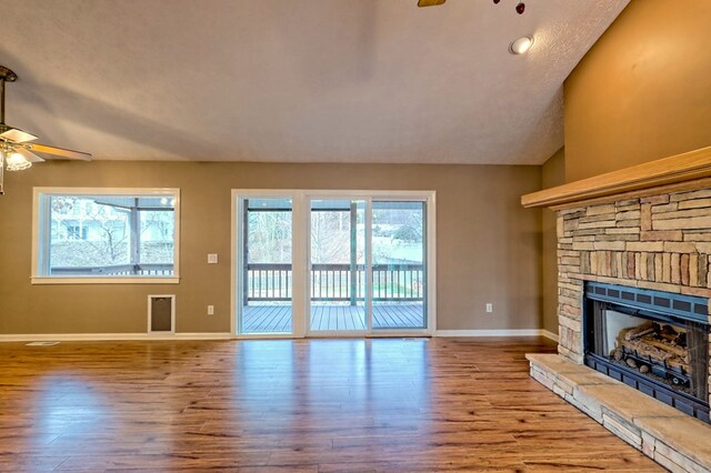 unfurnished living room with ceiling fan, a fireplace, lofted ceiling, and hardwood / wood-style flooring