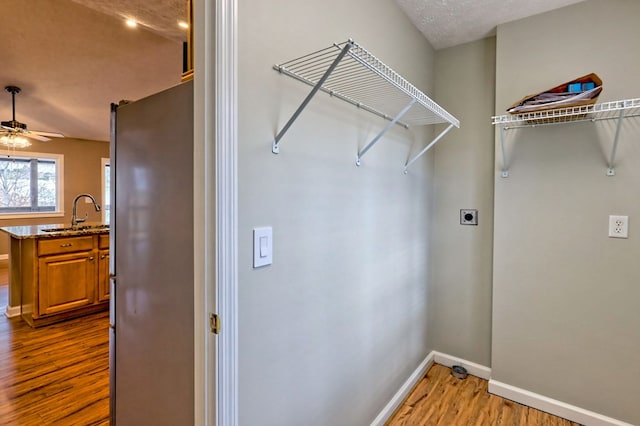 washroom featuring hardwood / wood-style floors, ceiling fan, electric dryer hookup, and sink