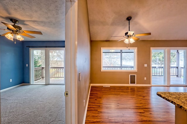 unfurnished living room with ceiling fan, a healthy amount of sunlight, and a textured ceiling