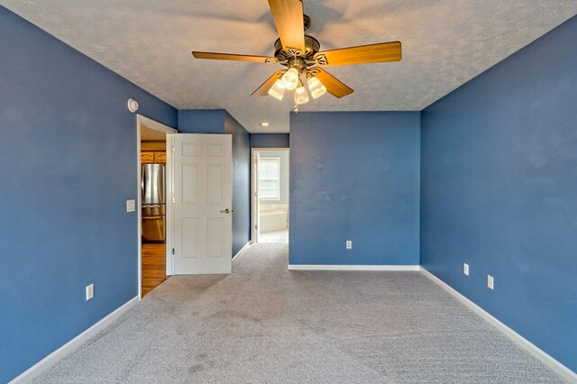 carpeted spare room featuring ceiling fan and a textured ceiling