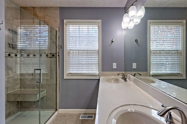 bathroom with a textured ceiling, vanity, tile patterned floors, and walk in shower