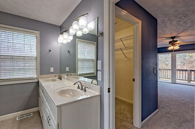 bathroom with tile patterned flooring, vanity, ceiling fan, and a textured ceiling