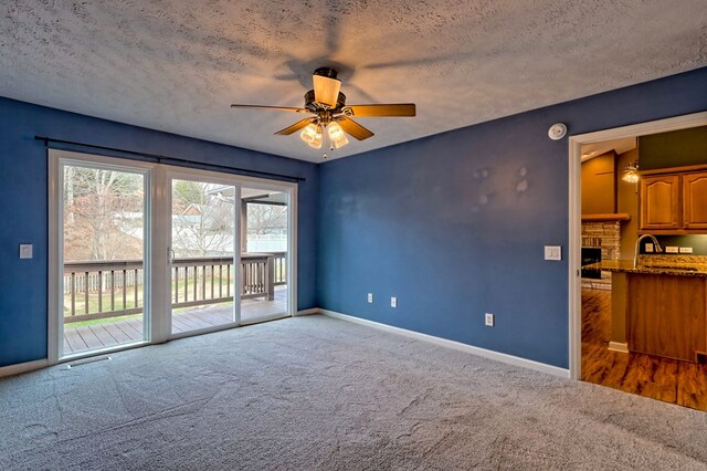 unfurnished living room with dark colored carpet, ceiling fan, and a textured ceiling