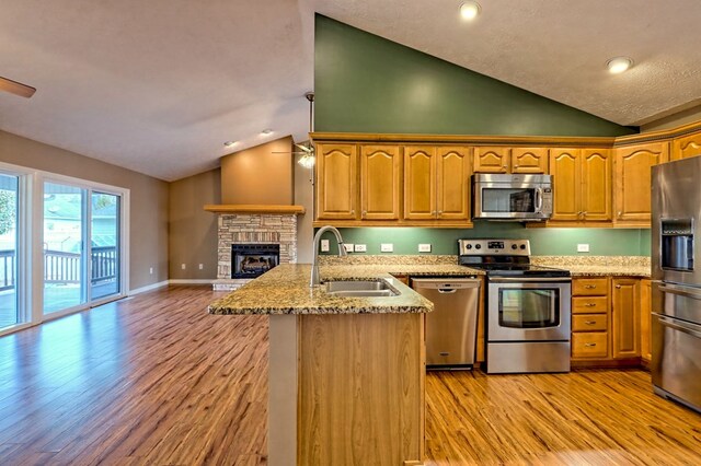 kitchen featuring light stone counters, light wood-type flooring, sink, and appliances with stainless steel finishes