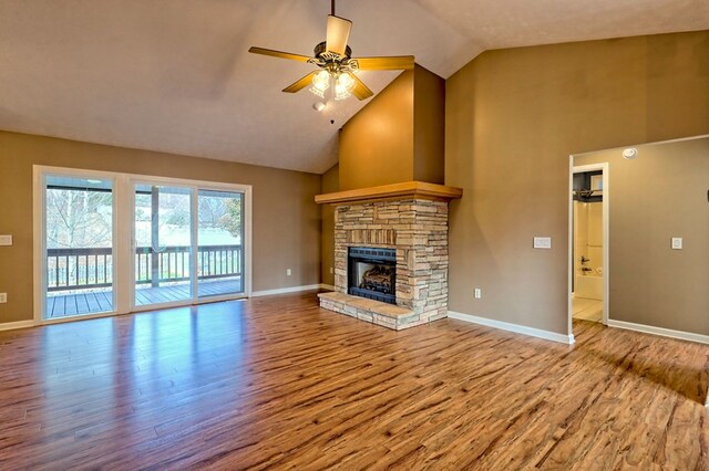 unfurnished living room with a stone fireplace, ceiling fan, wood-type flooring, and lofted ceiling