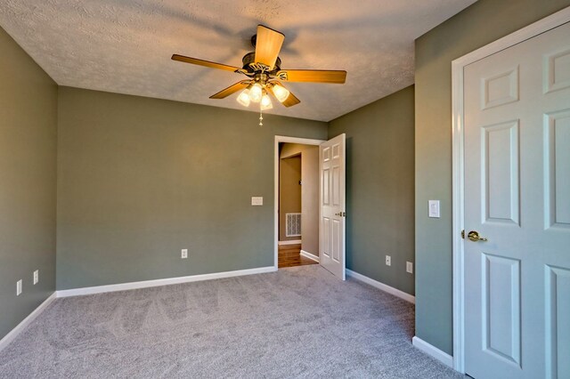 unfurnished bedroom featuring ceiling fan, light colored carpet, and a textured ceiling