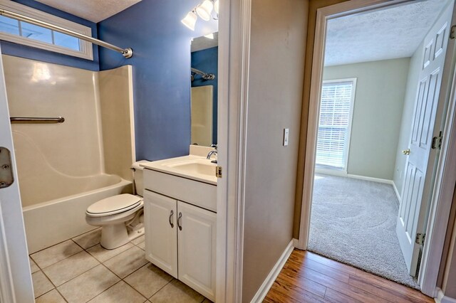 full bathroom featuring a textured ceiling, vanity, plenty of natural light, and  shower combination