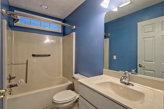 full bathroom with vanity, tub / shower combination, toilet, and a textured ceiling