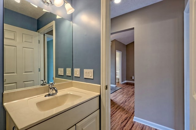 bathroom with hardwood / wood-style floors, vanity, and a textured ceiling