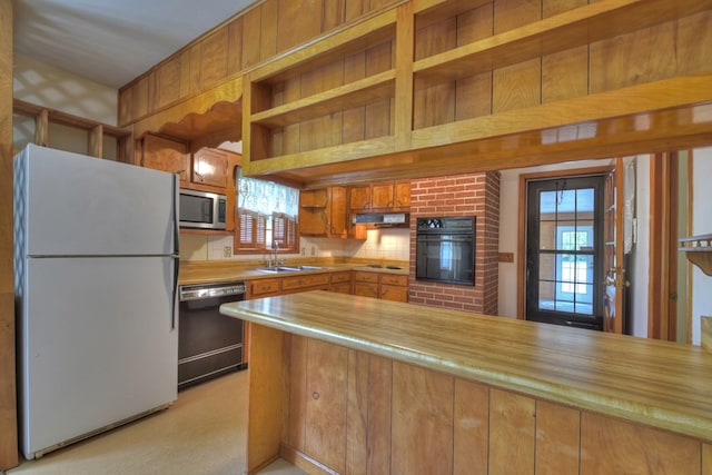 kitchen featuring kitchen peninsula, a healthy amount of sunlight, sink, and black appliances