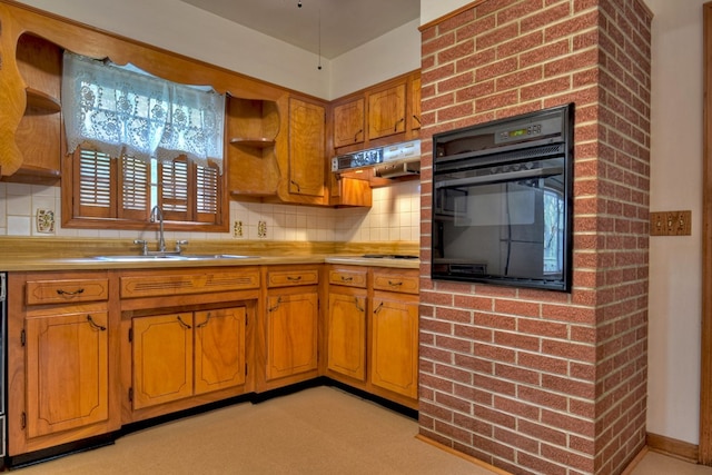 kitchen featuring tasteful backsplash, black oven, light carpet, and sink