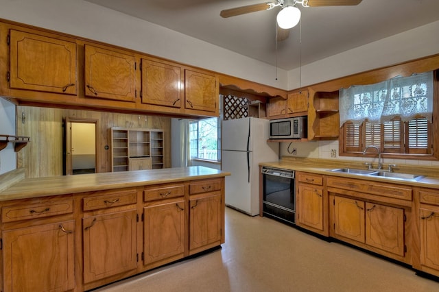 kitchen featuring ceiling fan, sink, black dishwasher, white refrigerator, and kitchen peninsula