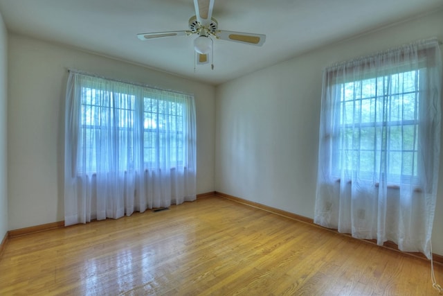 empty room with ceiling fan, a healthy amount of sunlight, and light hardwood / wood-style floors