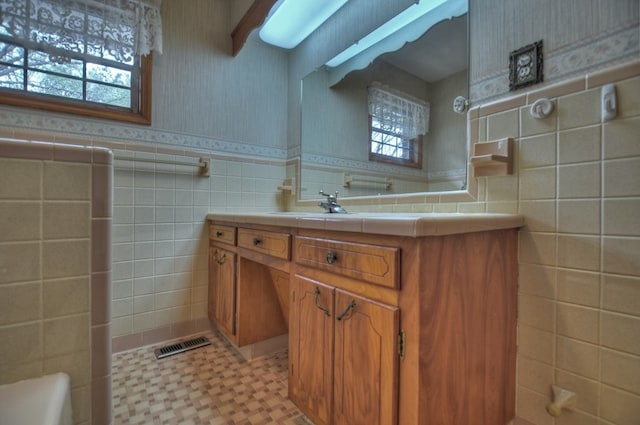 bathroom featuring vanity and tile walls