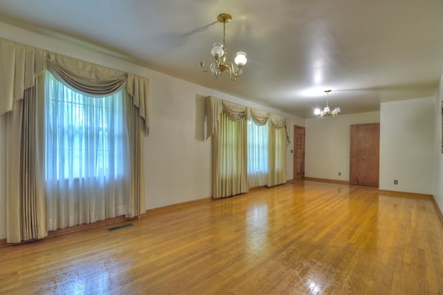 unfurnished room with wood-type flooring and a chandelier