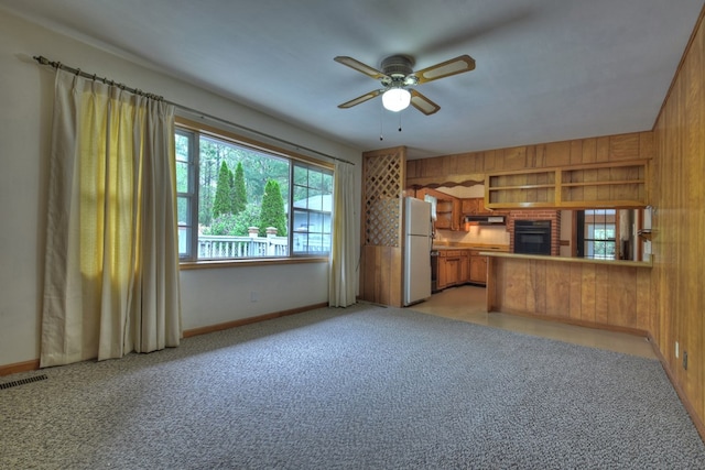 kitchen with kitchen peninsula, wood walls, ceiling fan, and white refrigerator