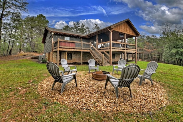 rear view of property with a fire pit, central AC, a wooden deck, and a lawn