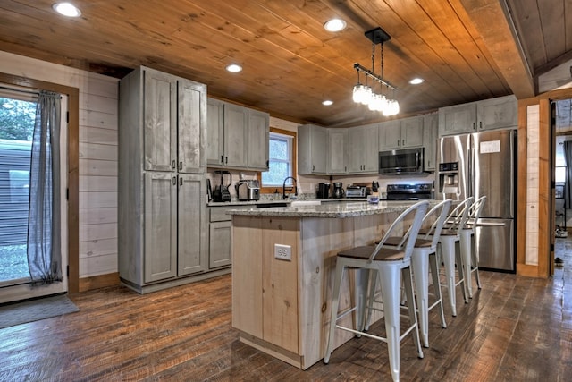 kitchen with light stone countertops, hanging light fixtures, wooden ceiling, a kitchen island, and appliances with stainless steel finishes