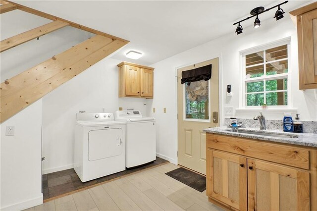 washroom with light hardwood / wood-style flooring, sink, cabinets, rail lighting, and washer and dryer