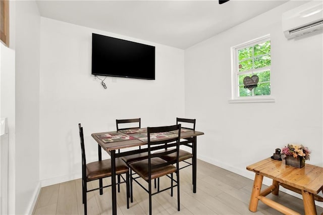 dining area featuring an AC wall unit and light wood-type flooring