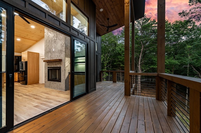 deck at dusk with a large fireplace and ceiling fan