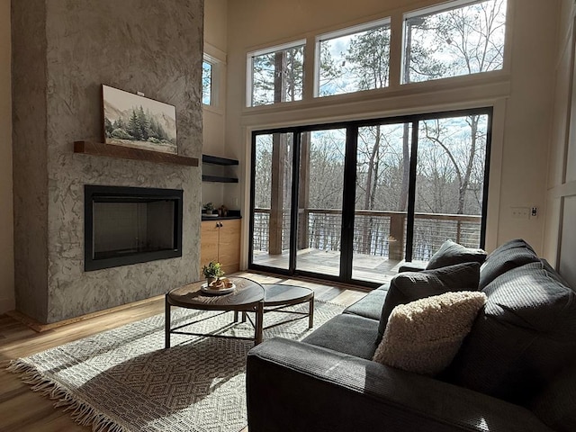 living room with hardwood / wood-style flooring, a large fireplace, and a high ceiling