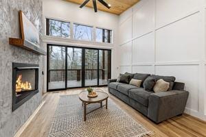 living room featuring a high ceiling, a healthy amount of sunlight, wooden ceiling, and light hardwood / wood-style flooring