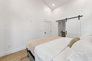 bedroom with a barn door and light wood-type flooring