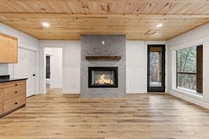 unfurnished living room featuring a large fireplace, wood ceiling, and light hardwood / wood-style flooring