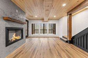 unfurnished living room with beamed ceiling, a large fireplace, hardwood / wood-style floors, and wooden ceiling