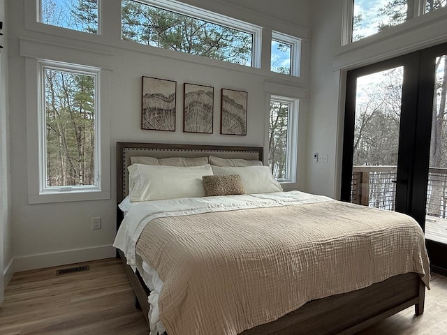 bedroom featuring hardwood / wood-style flooring, a towering ceiling, and multiple windows