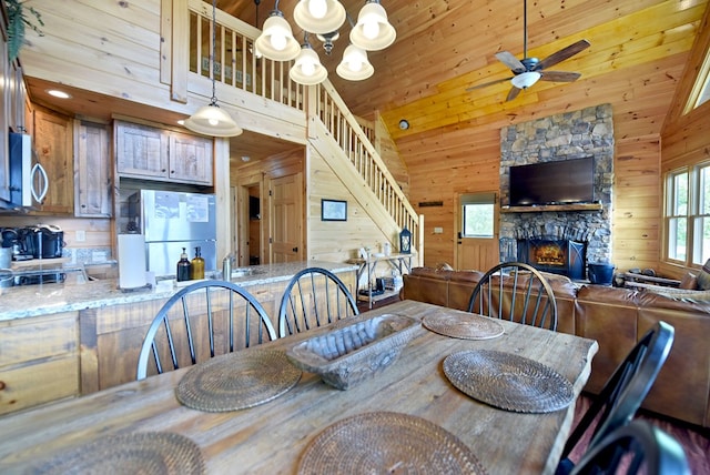 73 Rosiey Ln, Blue Ridge, GA 30513 - dining space featuring stairs, a fireplace, ceiling fan, wood walls, and a chandelier
