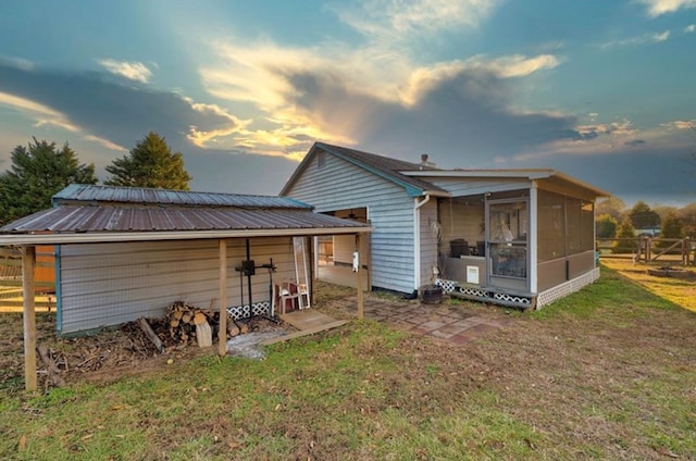 back house at dusk with a yard and a sunroom