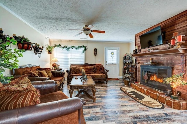 living room with a brick fireplace, a textured ceiling, ornamental molding, ceiling fan, and hardwood / wood-style floors