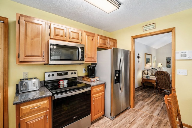 kitchen featuring stainless steel appliances, a textured ceiling, and light wood-type flooring