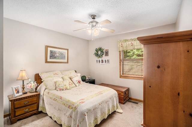 bedroom featuring ceiling fan, light carpet, and a textured ceiling