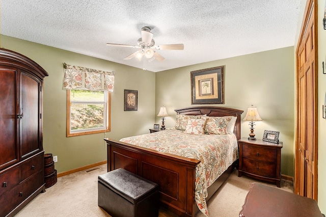 carpeted bedroom with ceiling fan and a textured ceiling