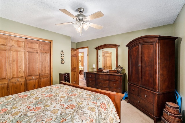 carpeted bedroom with ceiling fan, a textured ceiling, and a closet